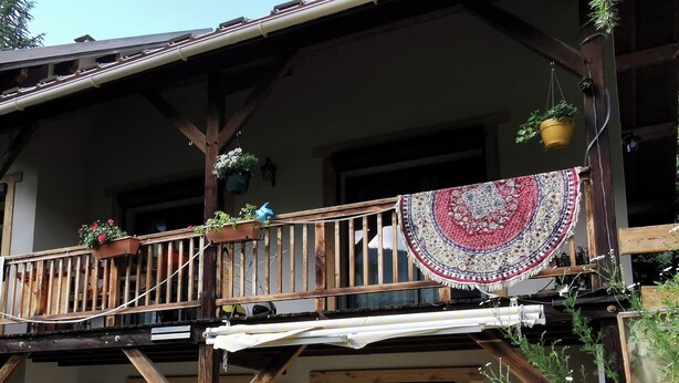 Un balcone in legno con piante in vaso e un vaso pensile di fiori.
