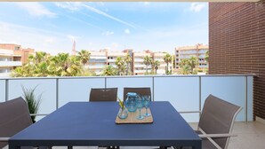 Un balcón con una mesa para dos, con vistas a un paisaje urbano con palmeras y edificios.