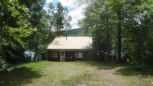 A single-story house with a sloped roof, a front door, and a small porch. - Beautiful Lakefront Cottage with Mountain Views (Dedham)