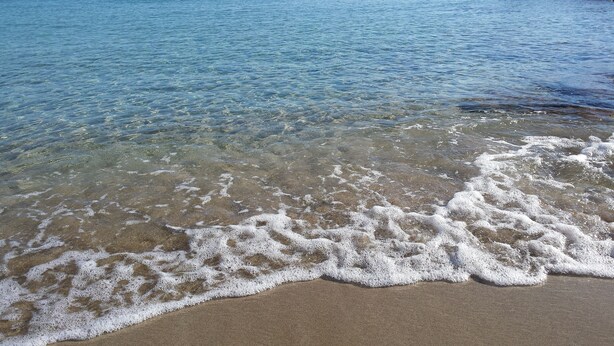 Une plage à l  ’eau claire et aux vagues douces.