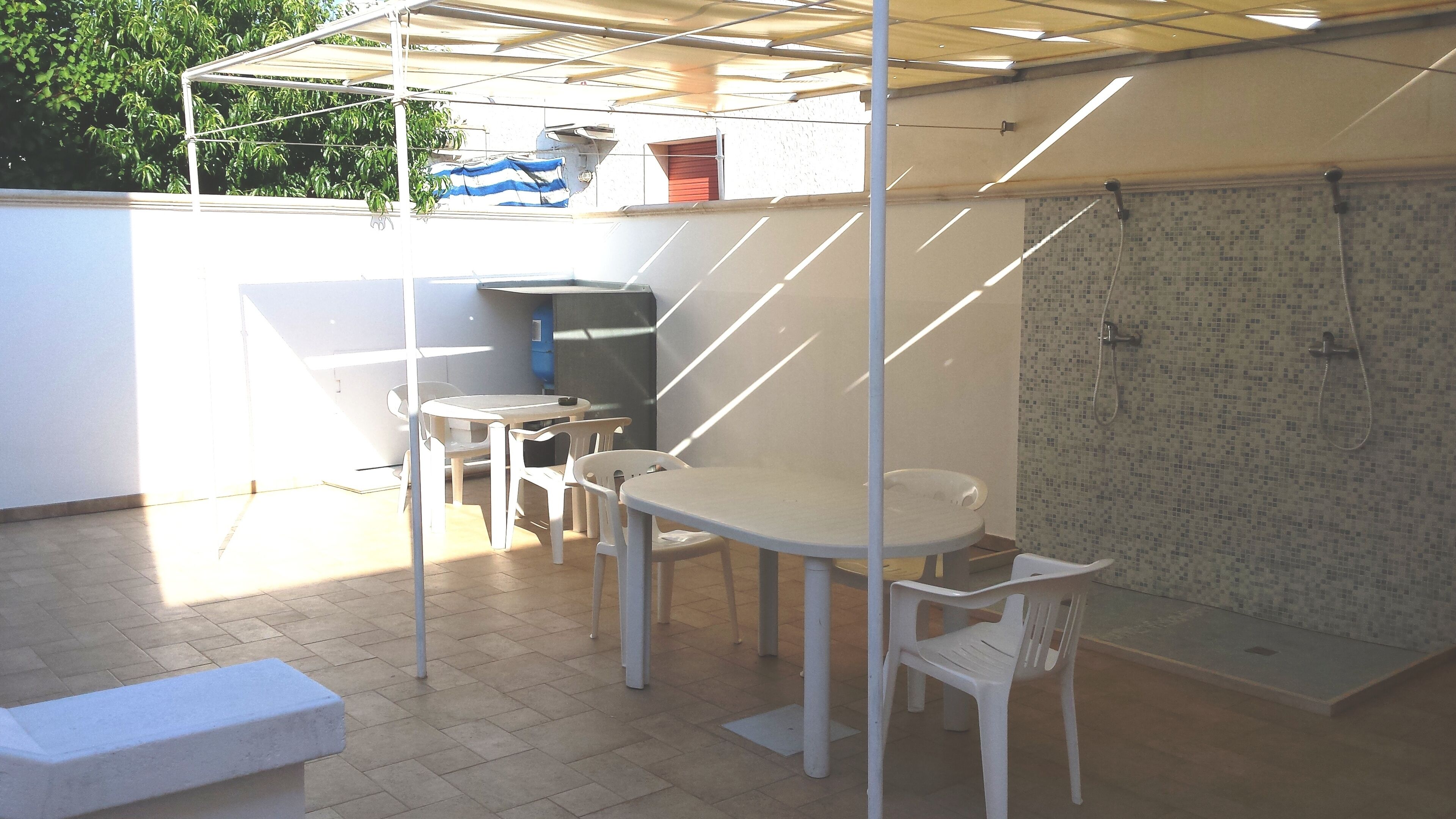 An outdoor patio with a table and chairs, a small sink, and a shower area.
