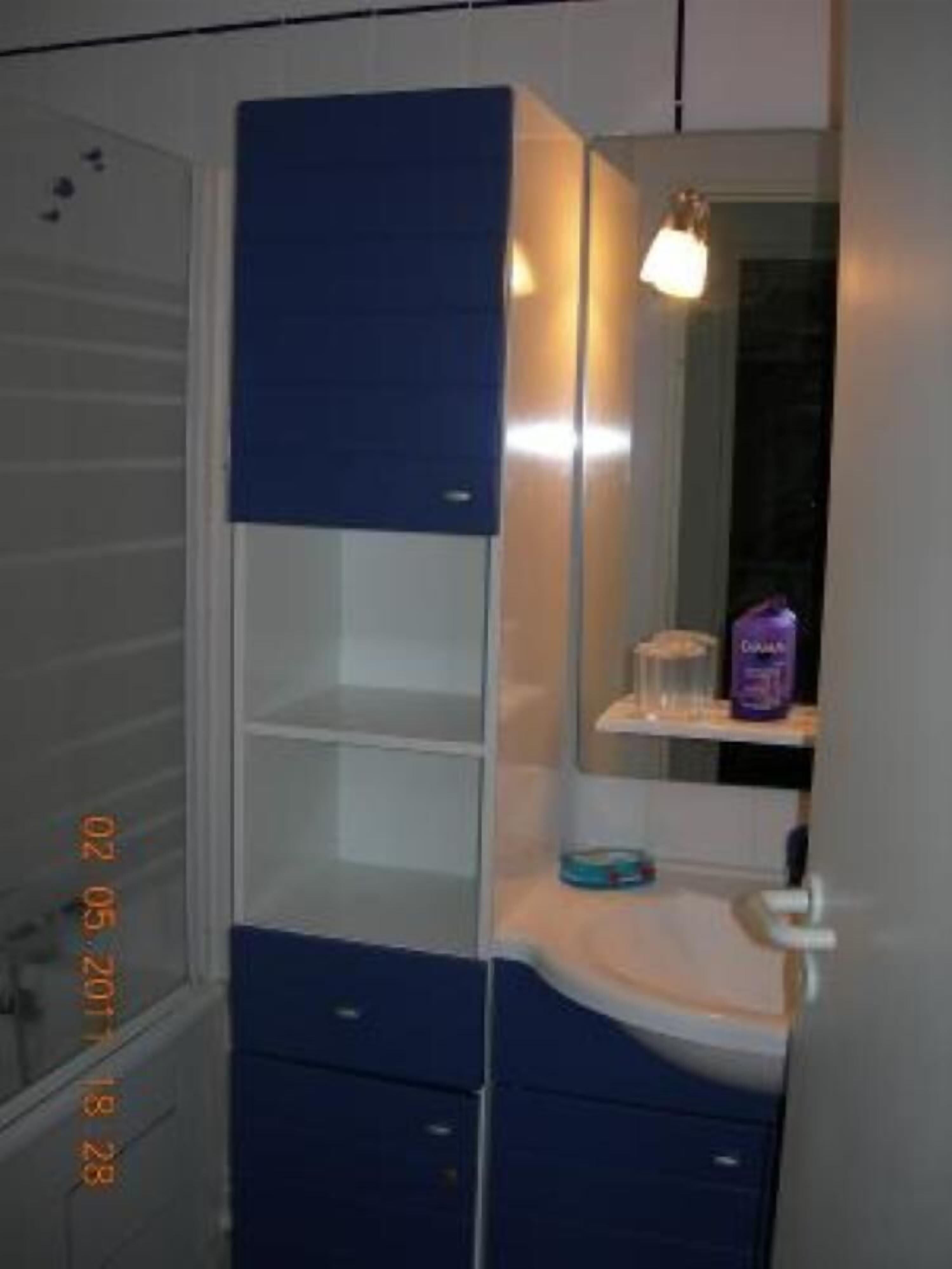 A bathroom with a blue vanity, a mirror, and a sink.