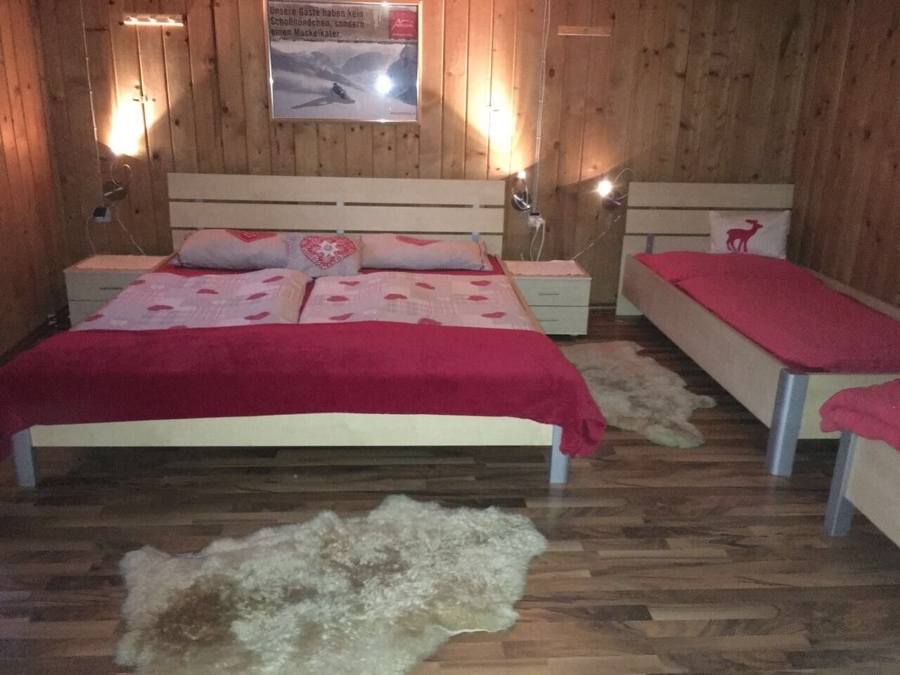 A wooden-paneled room with a bed, a bench, and a poster on the wall.