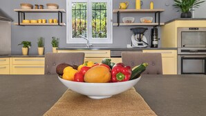 Una cocina moderna con una mesa de comedor en primer plano, mostrando un bol con verduras frescas.
