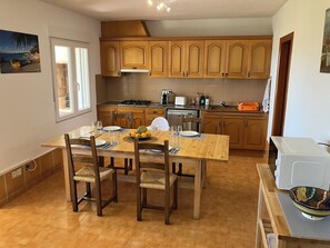 A kitchen with wooden cabinets, a dining table set with plates and glasses, and a microwave.