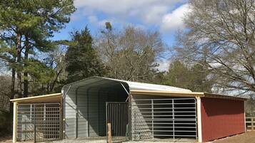 A metal barn with a covered entrance and a fenced area.