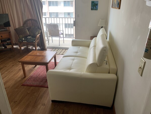 A living room with a white sofa, a wooden coffee table, and a red rug.
