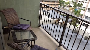 Een balkon met rieten meubels, waaronder twee stoelen en een tafeltje.