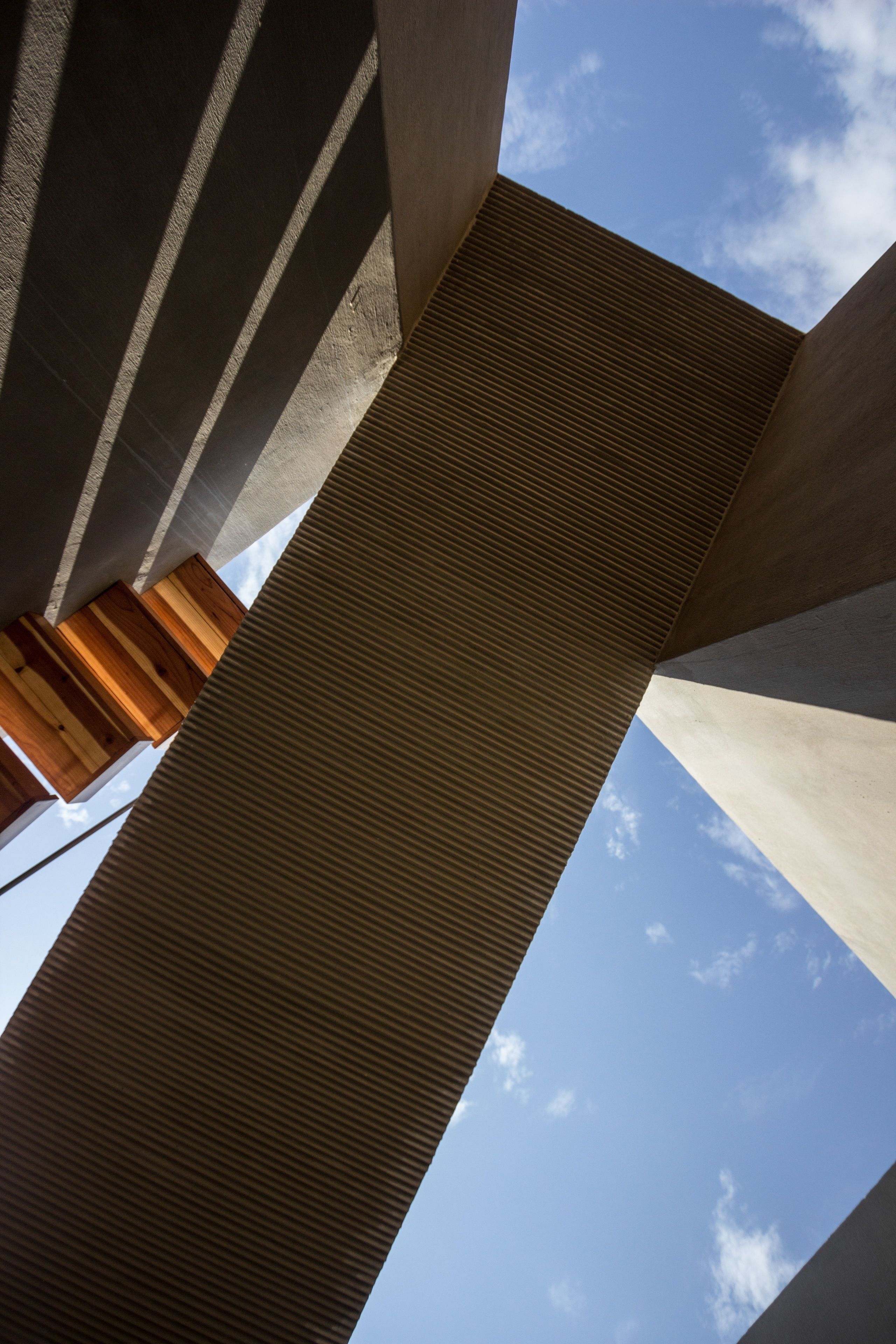 A view of a building's interior with concrete pillars and a wooden beam.