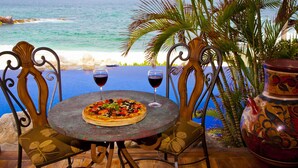 Une table à manger avec des chaises, une pizza et deux verres à vin.