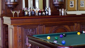 Une table de billard avec des billes, un bar avec des bouteilles et un lustre.