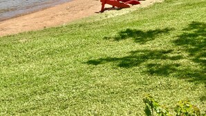A lakeside view with a grassy area and colorful Adirondack chairs along the shore. - Small but cozy apartment style lakefront home on Buchanan Dam with great views! (Buchanan Dam)
