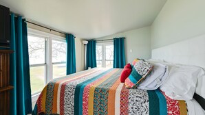 A bedroom with a large bed, teal curtains, and a view of the outdoors. - Small but cozy apartment style lakefront home on Buchanan Dam with great views! (Buchanan Dam)