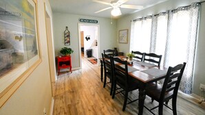A dining area with a wooden table and chairs, a ceiling fan, and a sign reading "BEACH HOUSE". - Small but cozy apartment style lakefront home on Buchanan Dam with great views! (Buchanan Dam)