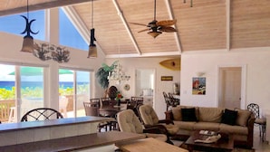 Amplia sala de estar con vista al océano, un comedor y una cocina con una isla grande.
