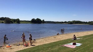A lakeside scene with people swimming and relaxing on the shore.