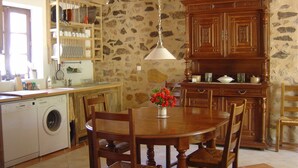 A kitchen with a washing machine, wooden cabinets, and a dining table with chairs.