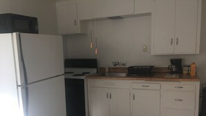 Eine kleine Küche mit Kühlschrank, Herd und weißen Schränken.