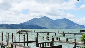 Eine Holzstege führt in einen ruhigen See, im Hintergrund erheben sich Berge.