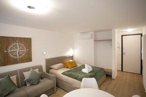 Ein modernes Schlafzimmer mit Bett, einer Couch, einem kleinen Tisch und einer Wand-Klimaanlage.