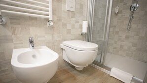 Ein modernes Badezimmer mit integriertem Bidet, Toilette und Duschkabine aus Glas.