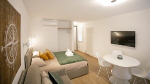 Ein modernes Zimmer mit Bett, Schreibtisch und Fernseher.