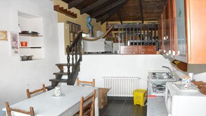A kitchen with a dining area, wooden staircase, and a radiator. - JOY VILLA APARTMENT LOFT (Acqui Terme)