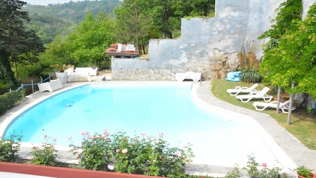 A swimming pool with lounge chairs and a stone wall. - JOY VILLA APARTMENT LOFT (Acqui Terme)