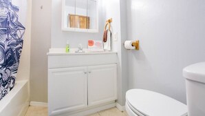 Un baño con lavamanos, espejo e inodoro blancos.