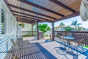 A covered outdoor patio with wooden flooring, metal chairs, a round table, and a pergola overhead. - 2330/B Comfy 2 bed dual master with Backyard! (San Diego)