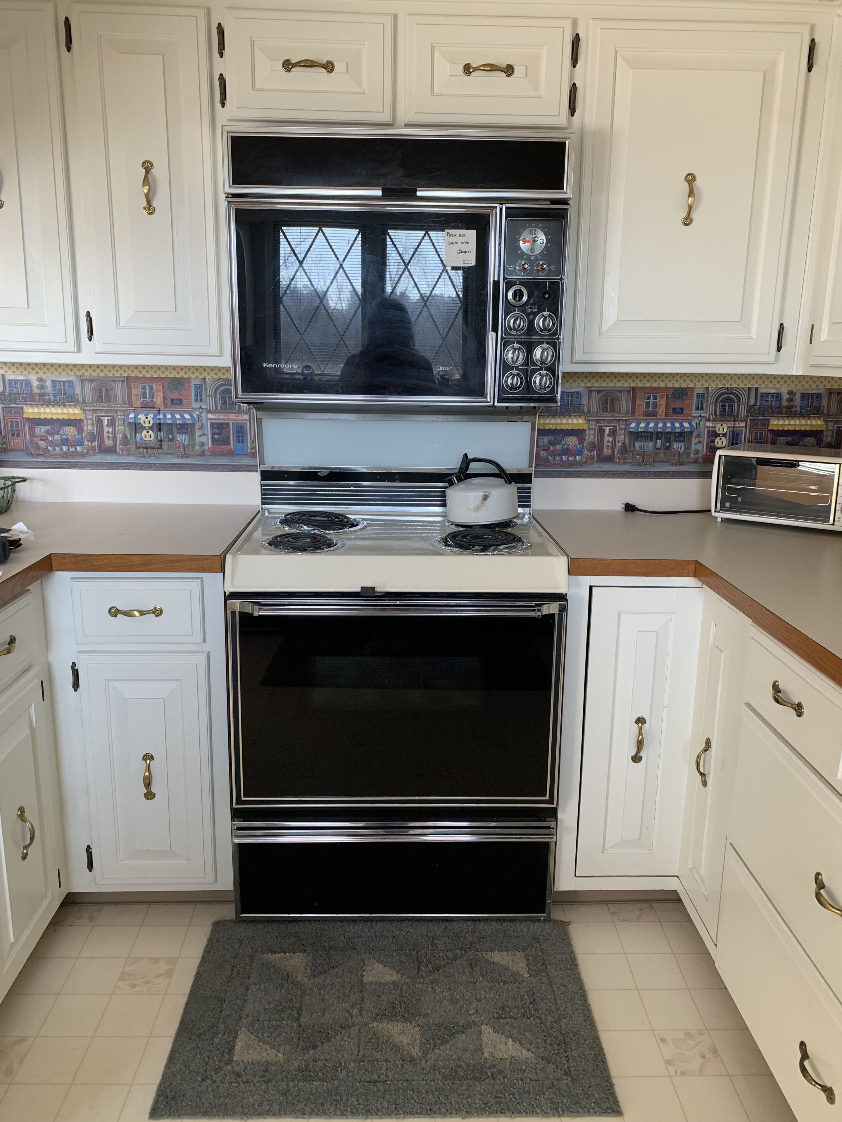A kitchen with white cabinets, a microwave, a stove, and a toaster.
