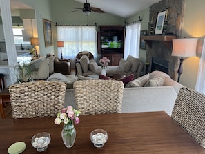 Una sala de estar con chimenea, televisor y comedor con mesa y sillas.