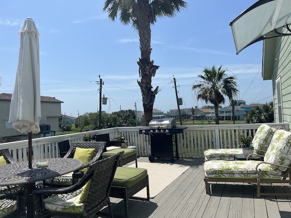 Una terraza con mobiliario exterior, una parrilla y vistas del barrio.