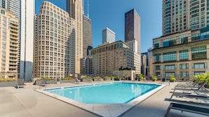 Ein Pool auf dem Dach mit Liegestühlen und Blick auf die Stadt.
