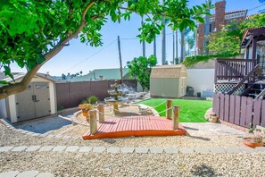 A backyard with a wooden deck, a small fountain, and a shed.