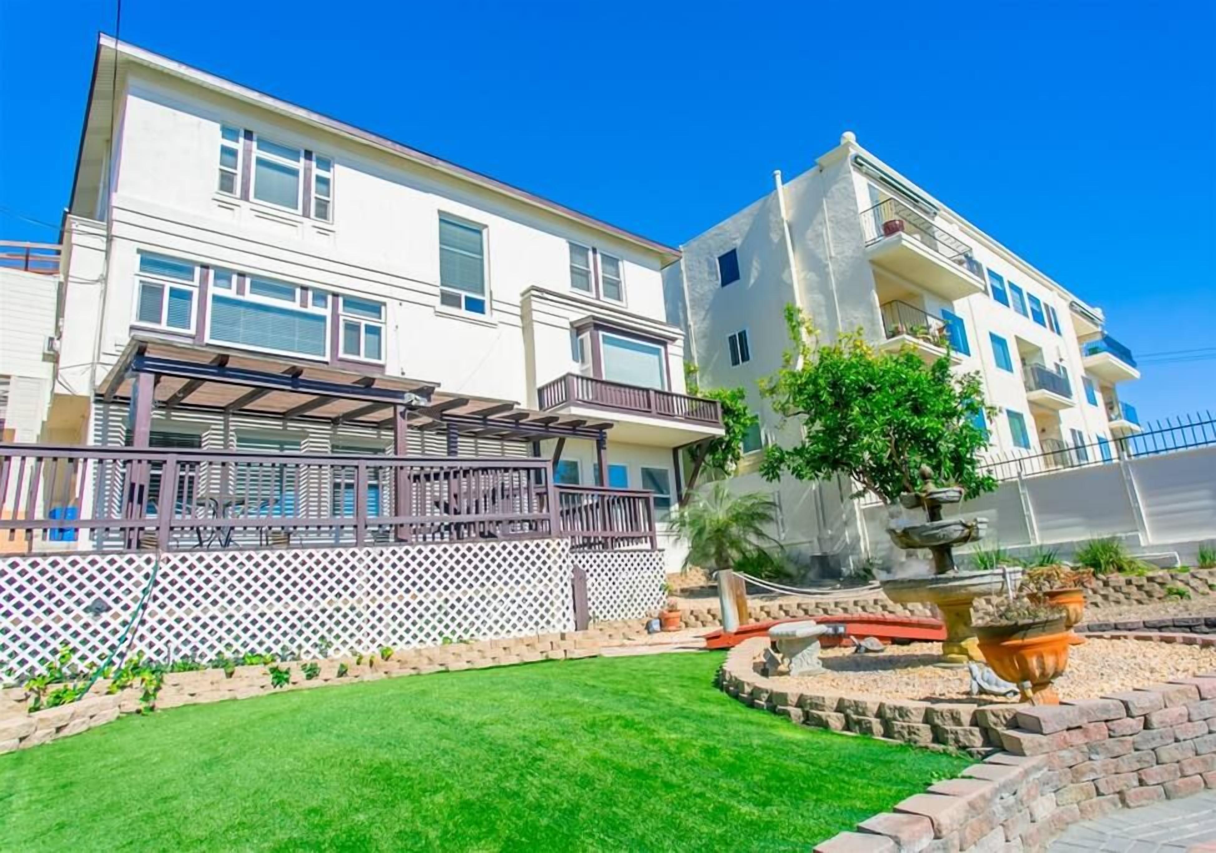 A multi-story residential building with a covered patio and a landscaped garden with a fountain.