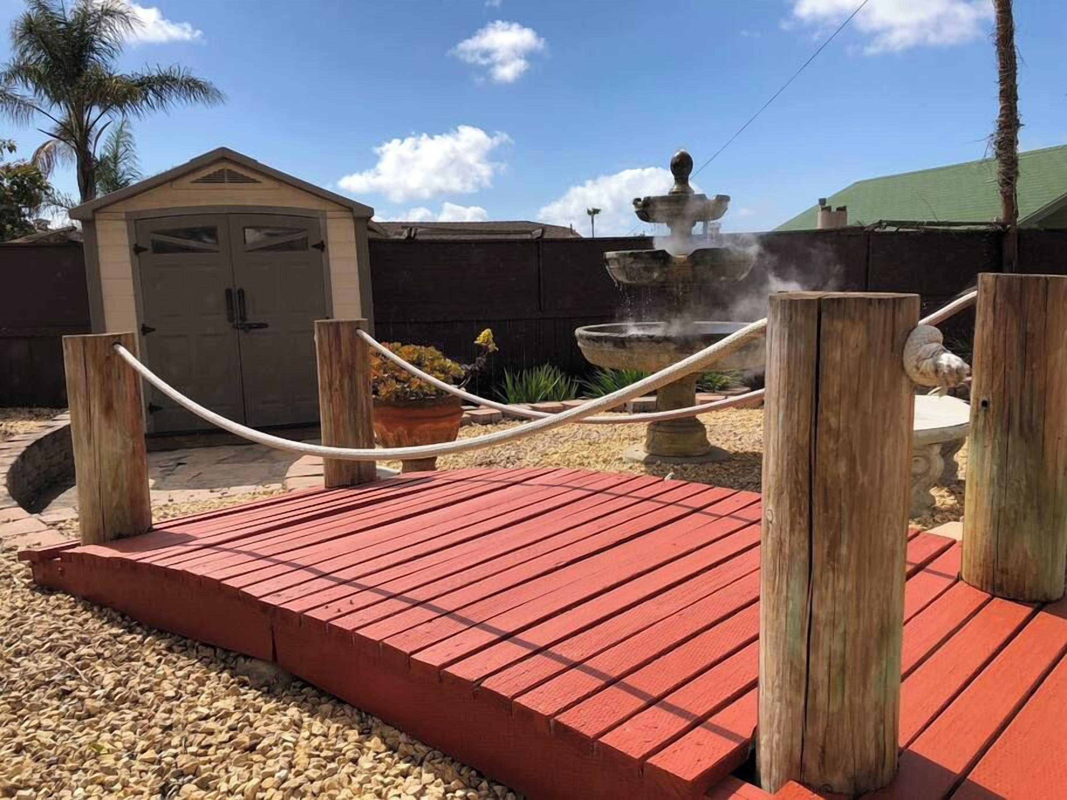 A red wooden deck with a fountain in the background.