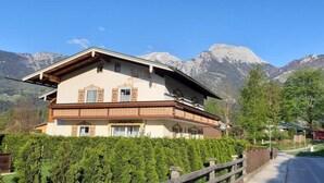 Un chalet a due piani con tetto spiovente, sullo sfondo di montagne.