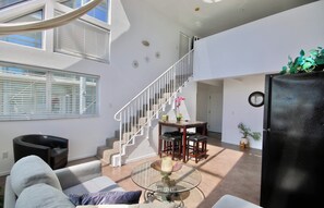 A modern living space with a staircase, seating area, and a dining table. - 301 Amazing Sky Loft in Little Italy! (San Diego)