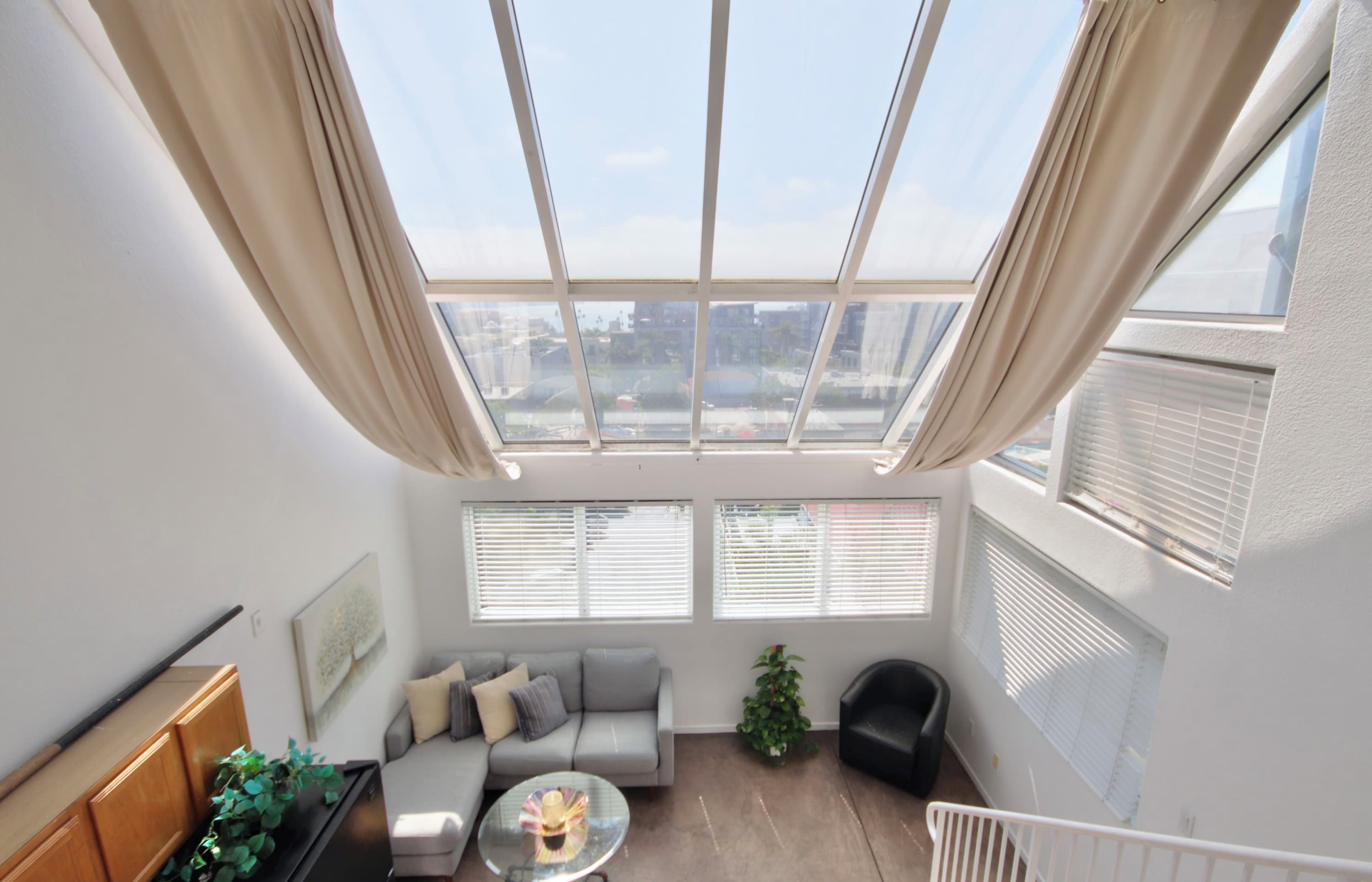 A modern living room with a skylight, a sofa, a coffee table, and a plant.