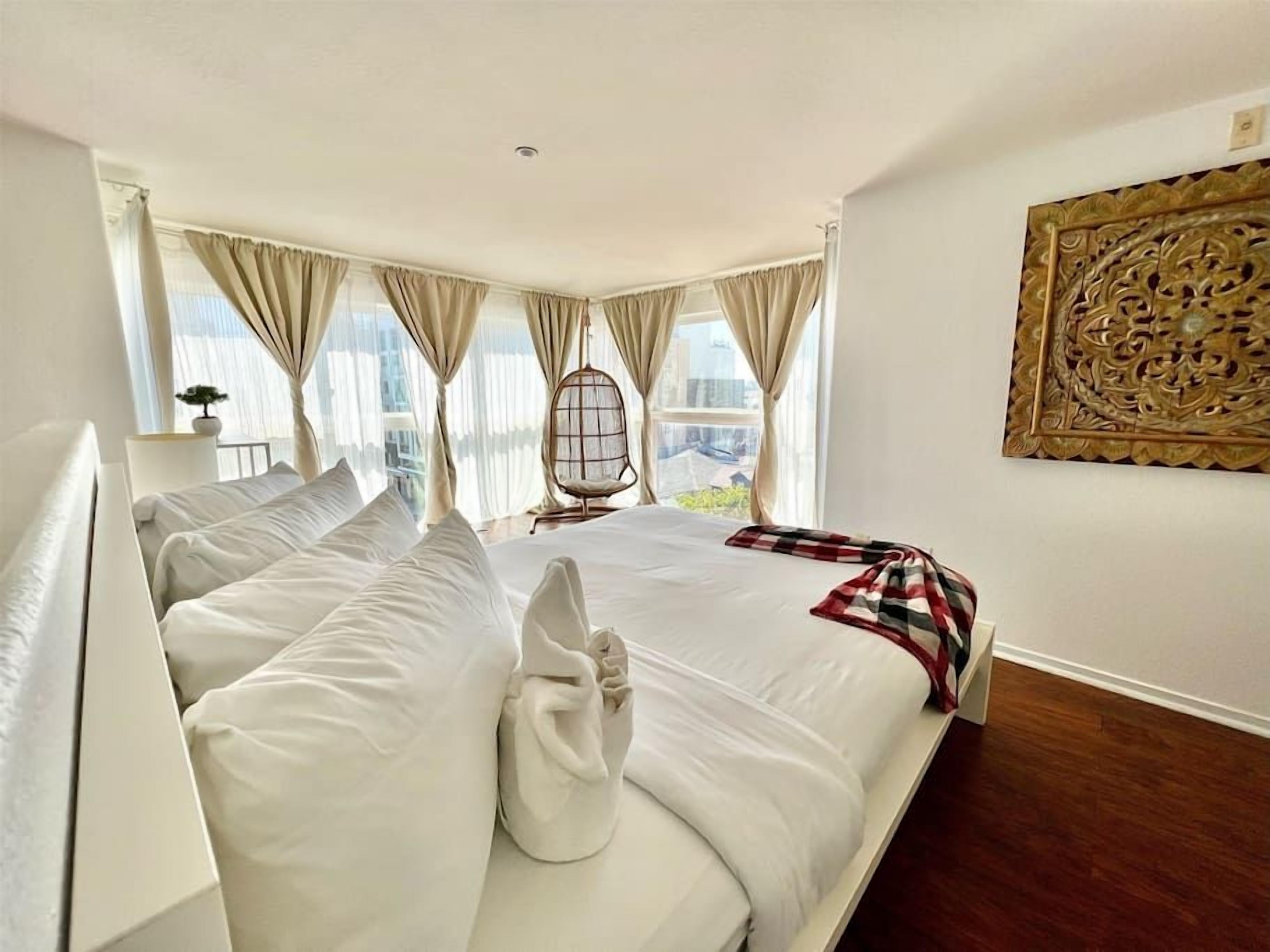 Un dormitorio amplio con una cama grande, una silla y vistas a la ciudad.
