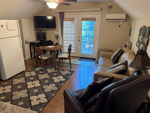 A compact living space with a kitchenette, a dining area, a sofa, and a TV.