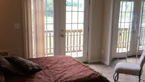 A bedroom with a bed, a chair, and a balcony with a wooden railing. -  Activity all around!  stay up in the trees, Take in the activity or just chill
 (Glasgow)