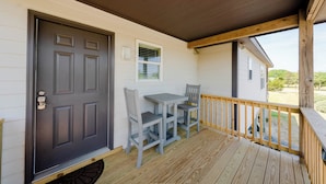 A wooden deck with a gray door and a small table with two chairs. - 3-bedroom, 2-bathroom apartment. Walk to beach and access to REAL Watersports (Waves)