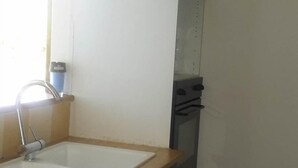 Une cuisine de taille réduite, équipée d’un évier, d’une cuisinière et de placards.
