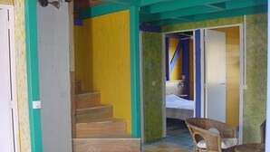 Una habitación con escalera de madera, una cama y una silla.