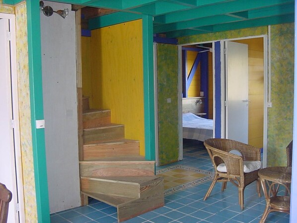 Ein Zimmer mit einer Holztreppe, einem Bett und einem Sessel.