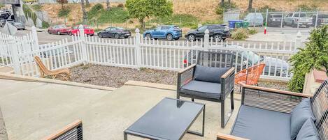 An outdoor seating area with wicker furniture and a white fence.