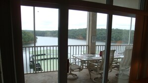 A balcony with a table and chairs, overlooking a lake and forested area. - 6102 Towers. Luxury 6th Floor Towers, Beautifully Decorated. Free Wifi (Osage Beach)