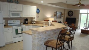 A kitchen with white cabinets, a stone island, and bar stools. - 6102 Towers. Luxury 6th Floor Towers, Beautifully Decorated. Free Wifi (Osage Beach)